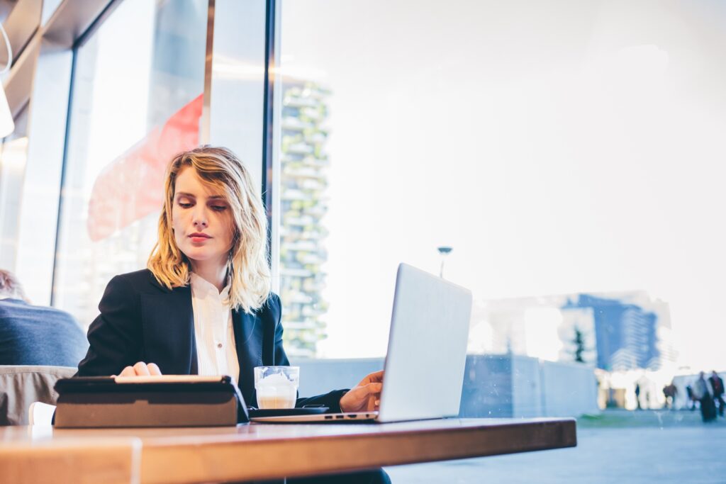 Young blonde business woman using computer remote working cafeteria